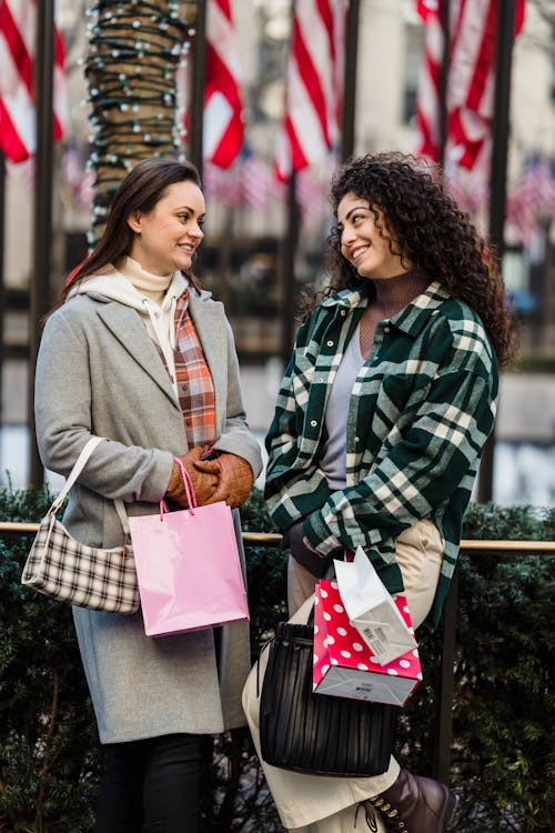 Smiling young diverse female millennials chilling on street after shopping