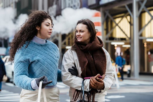 Two women walking and chatting on an urban street, radiating friendship and style.