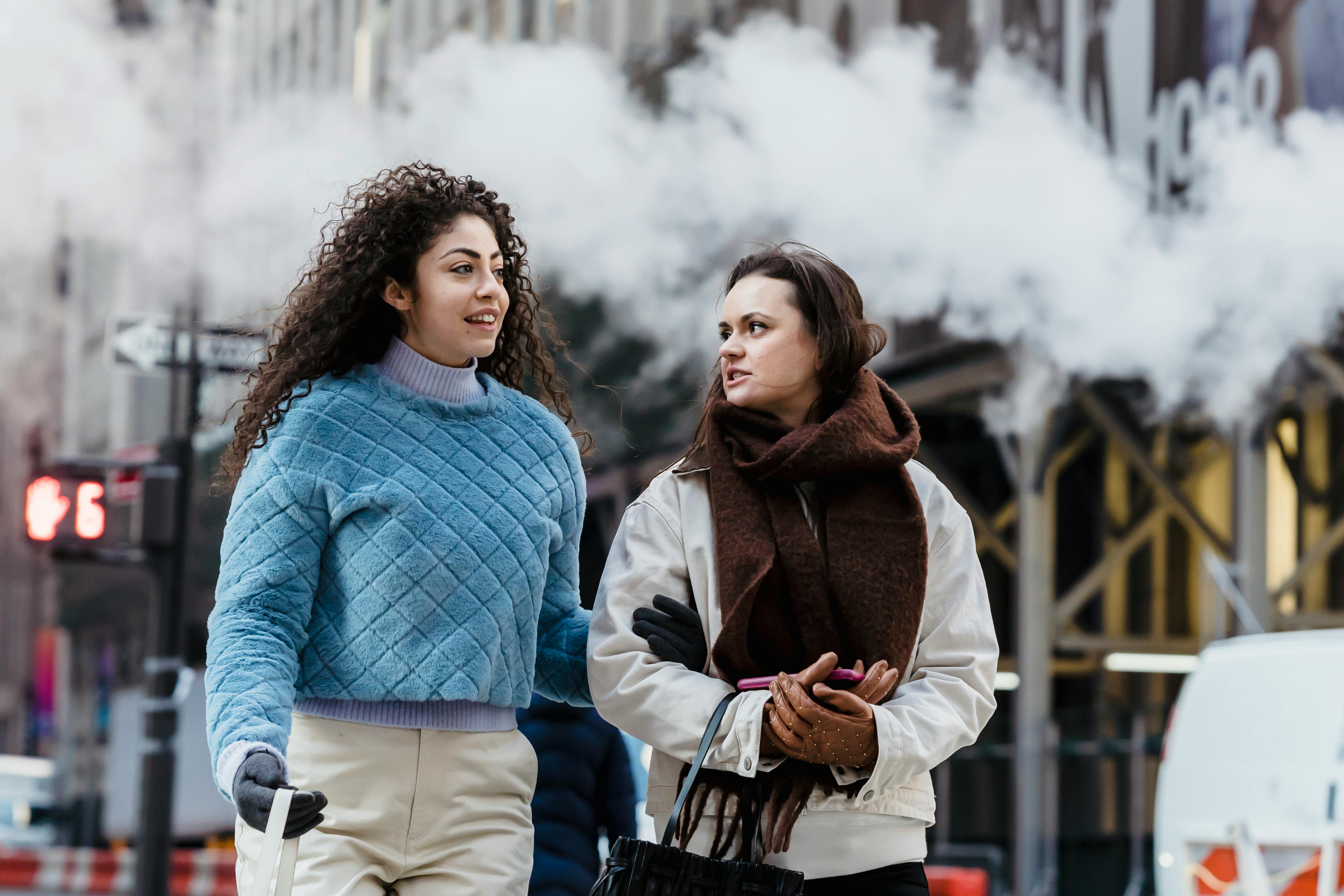 young cheerful friends in trendy warm clothes chatting and walking