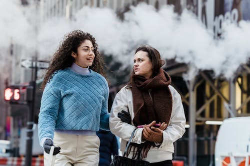 Free Young cheerful friends in trendy warm clothes chatting and walking Stock Photo