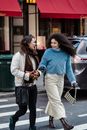 Amazed young friends in trendy clothes talking and crossing urban asphalt road of street in daytime