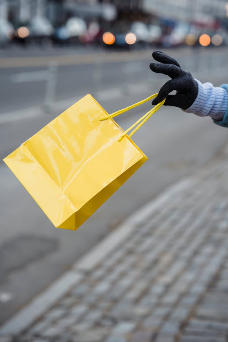 Woman In Glove With Bright Yellow Gift Bag