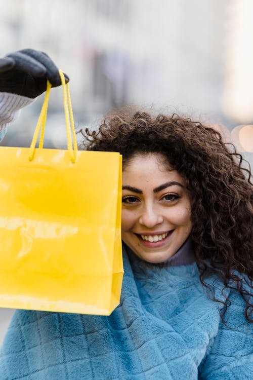 Cheerful woman with bright yellow gift bag