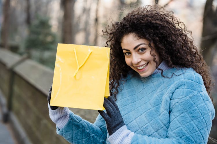 Young Woman With Bright Yellow Gift Bag In Hands