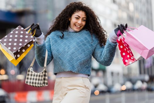 Delighted young woman with bright gift bags after shopping