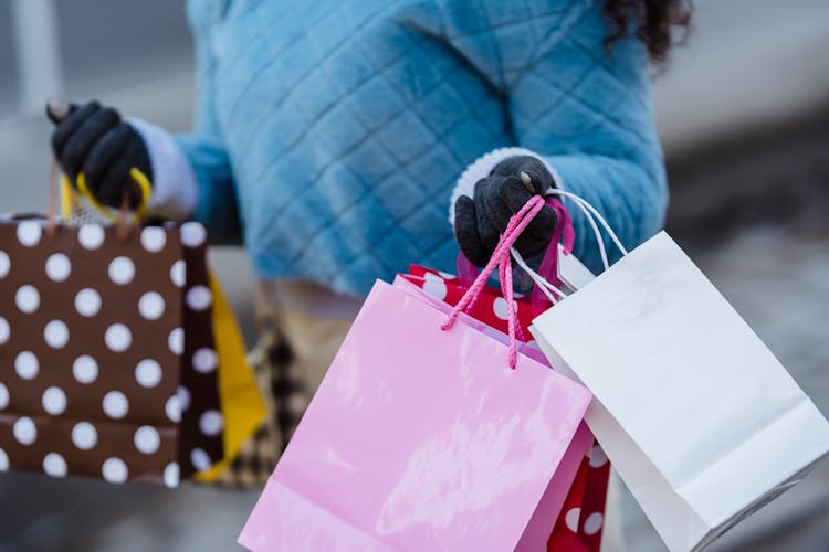 Woman In Gloves Carrying Bright Gift Bags