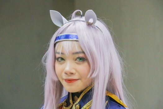 Close-up portrait of an anime cosplayer with pastel hair and vibrant costume.