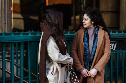 Women in stylish outfits talking near subway