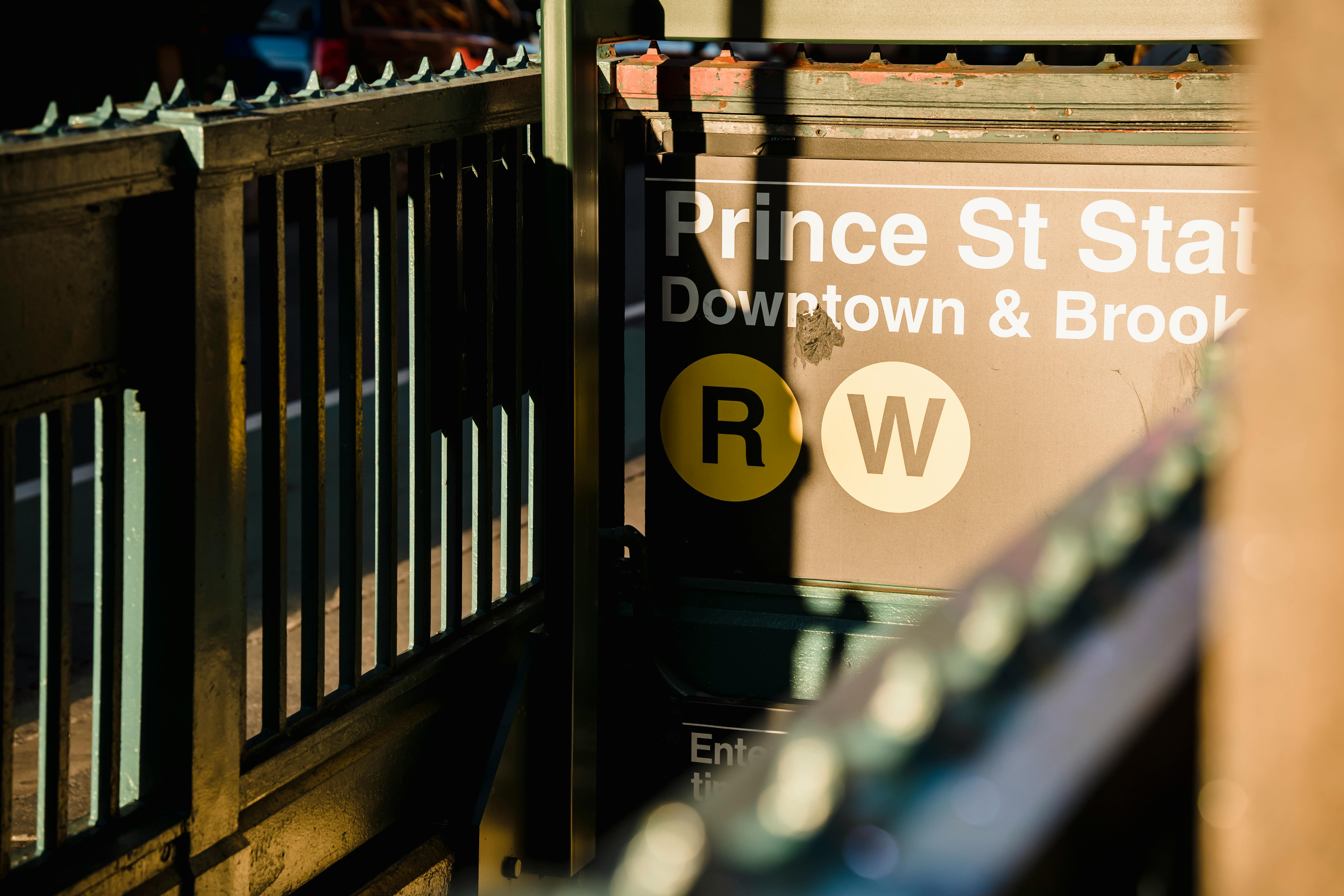 Inscription with text near subway entrance with metal railing of fence in daytime