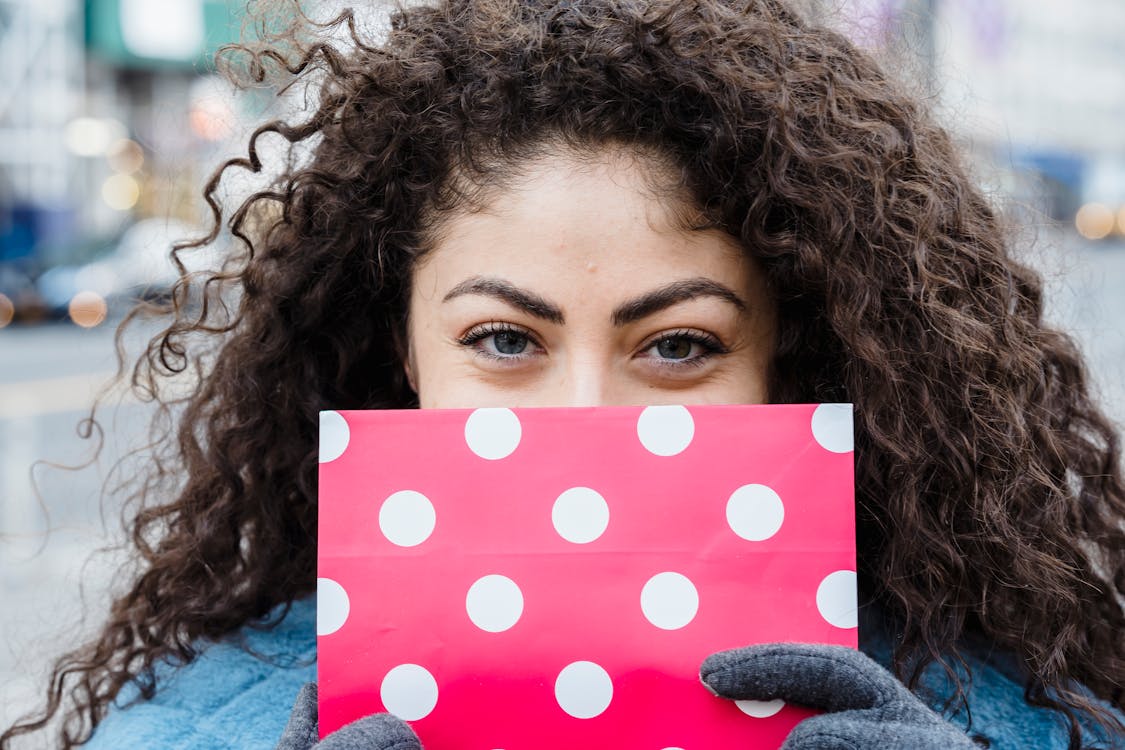 Free Woman with wrapped pink gift bag and curly hair Stock Photo
