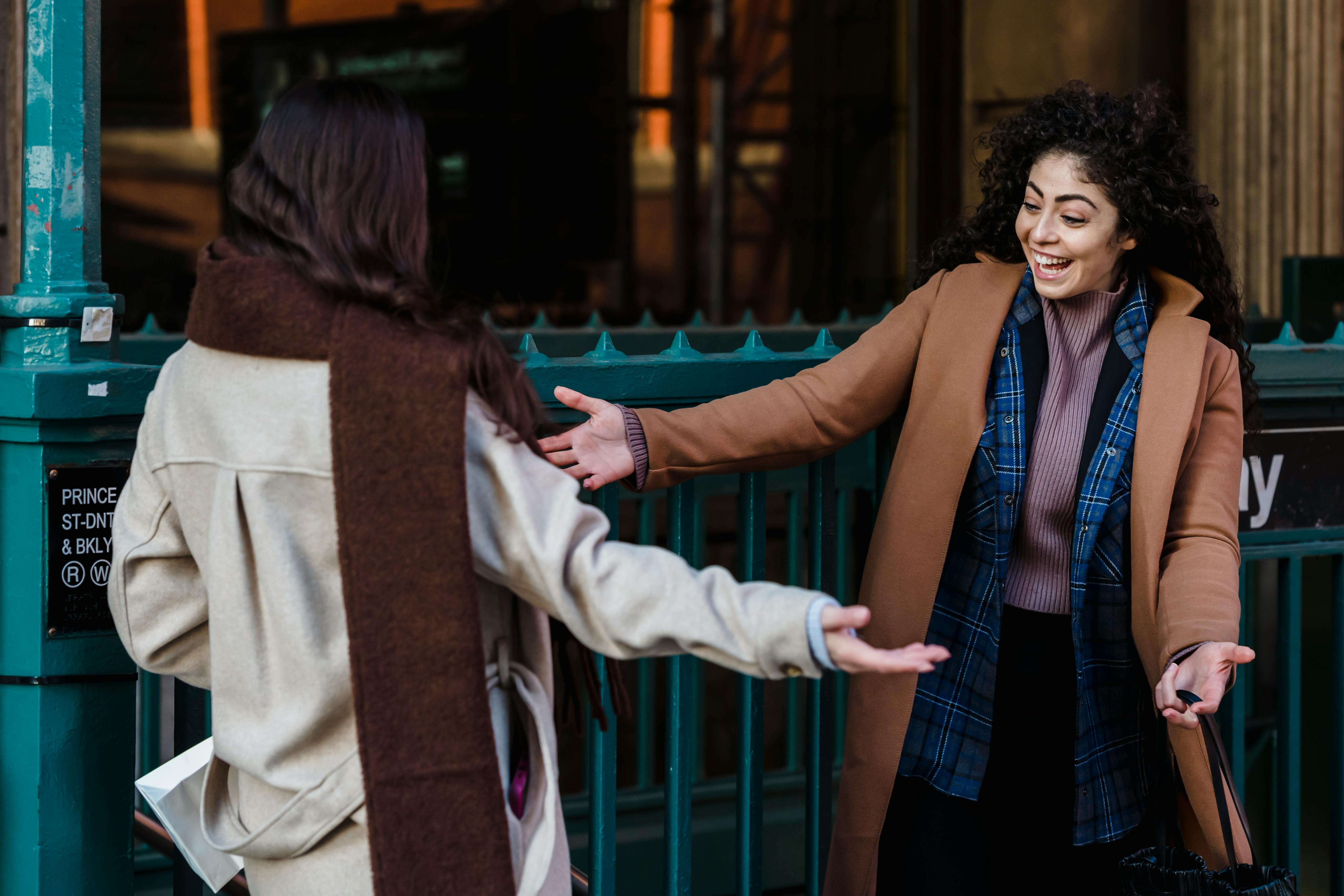 cheerful women hugging at meeting on street