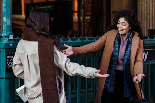 Cheerful women hugging at meeting on street