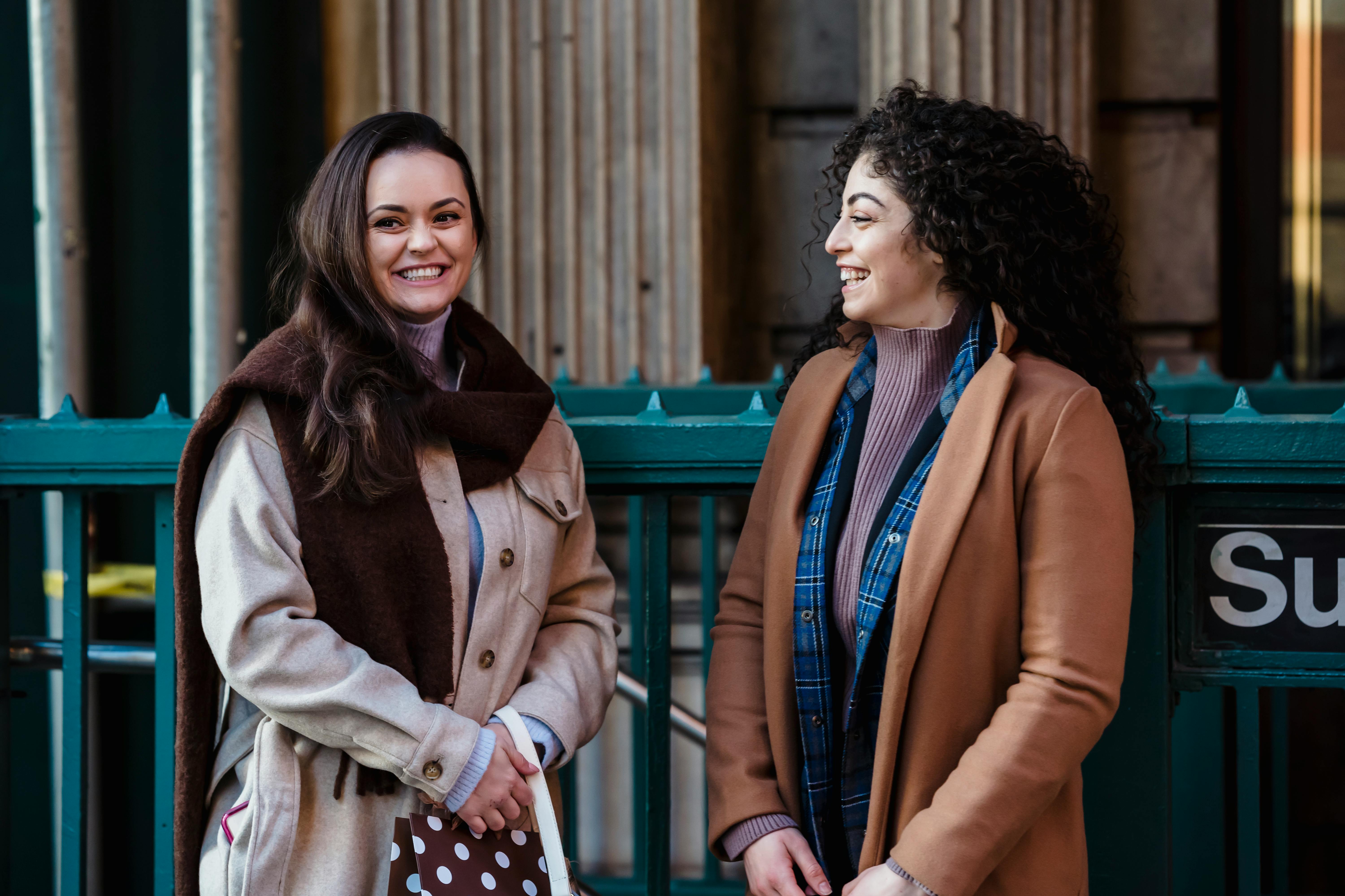 young happy women talking and smiling on street