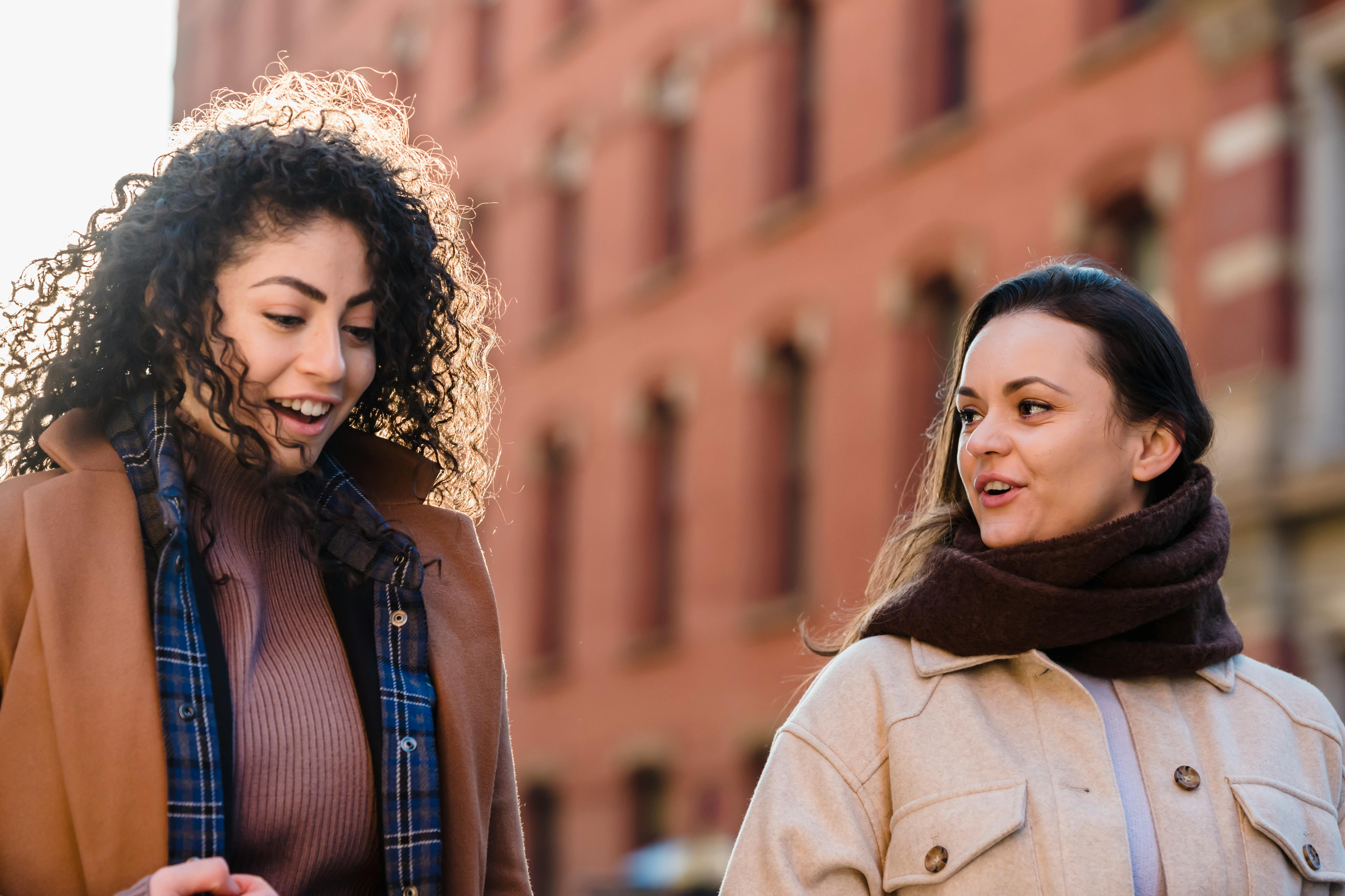 happy diverse females strolling on street and chatting