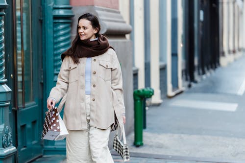 Confident young female shopper strolling on city street with gift bags