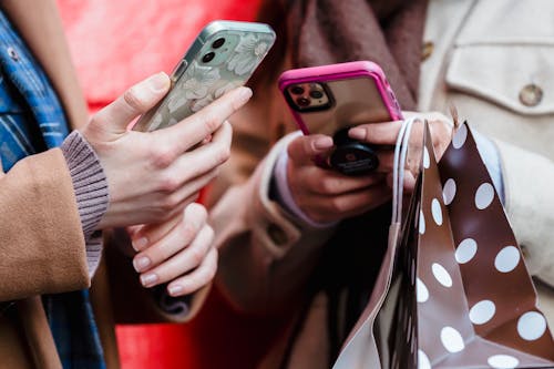 Unrecognizable ladies messaging smartphones on street