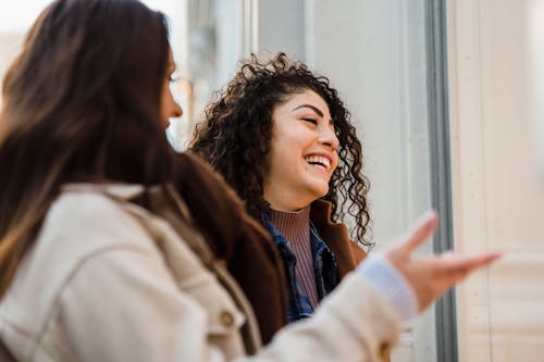 Cheerful young diverse ladies laughing on street