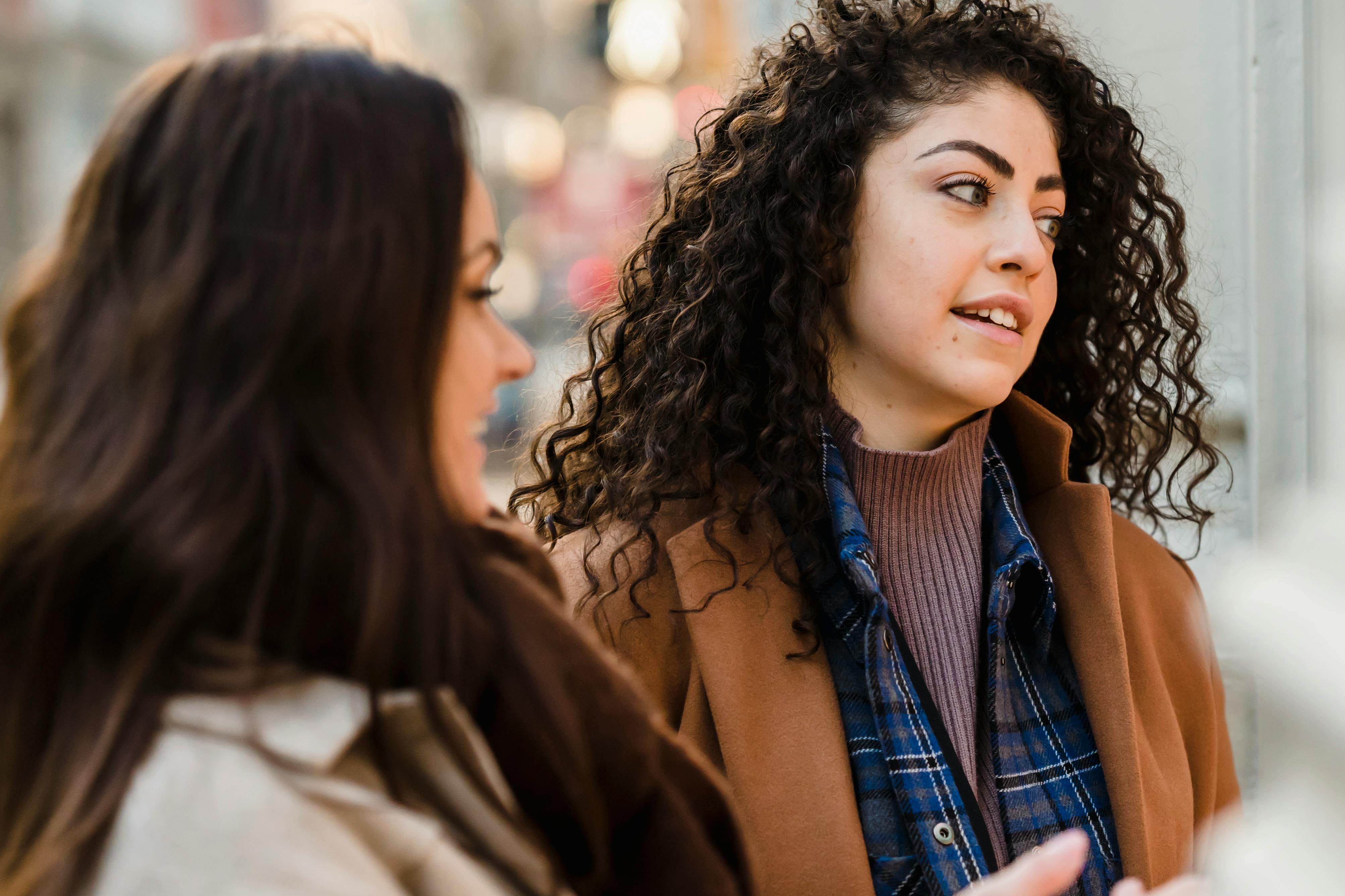 dreamy young diverse female friends standing on street and looking away