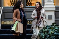 Amazed young multiracial women gossiping while strolling on street with shopping bags