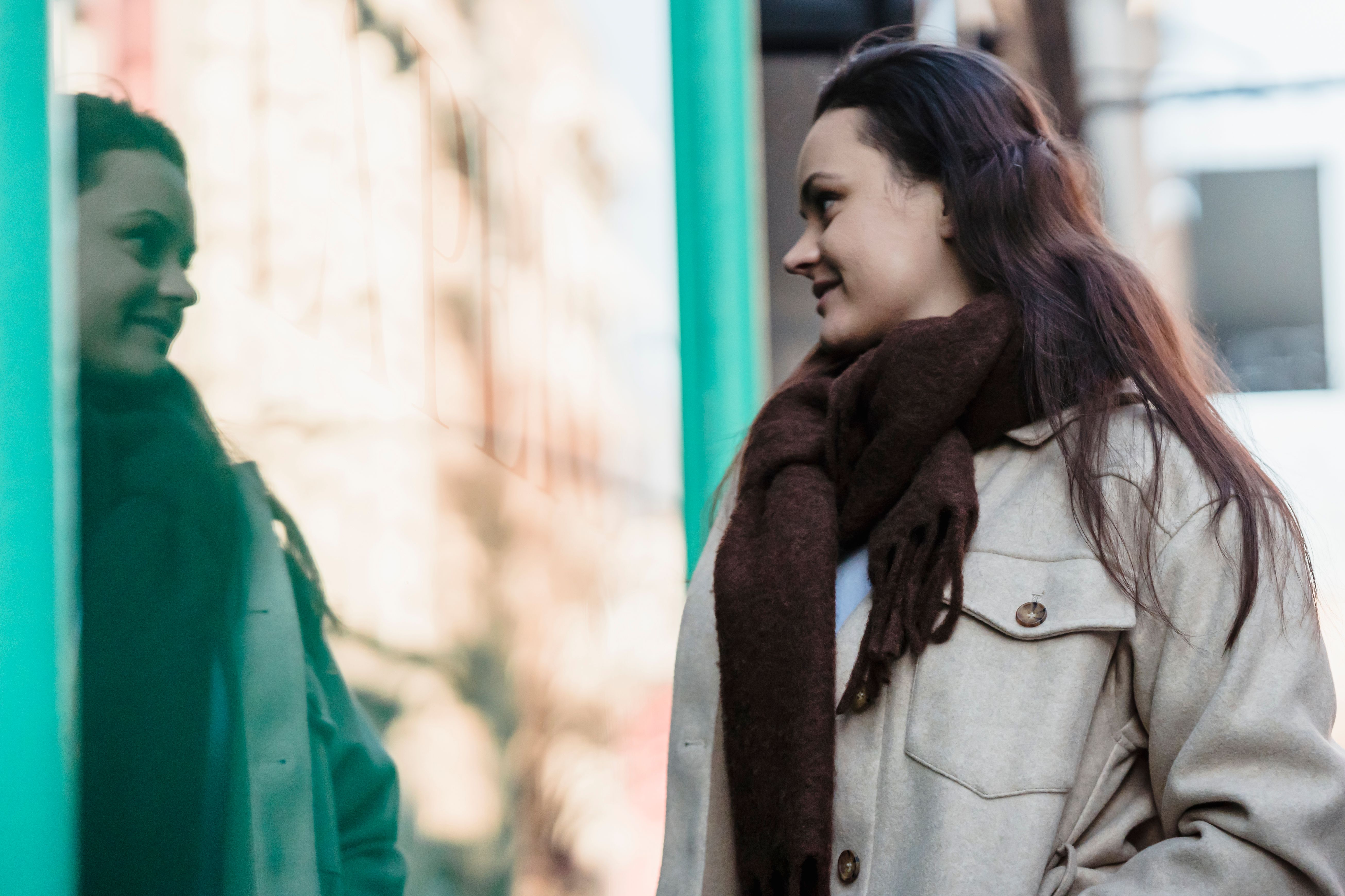 Woman in outerwear standing near glass wall · Free Stock Photo