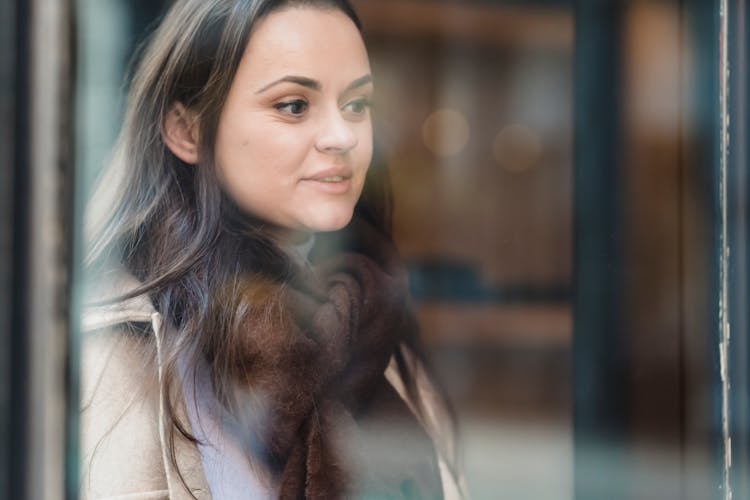 Smiling Woman In Tied Warm Scarf Standing Near Glass Building