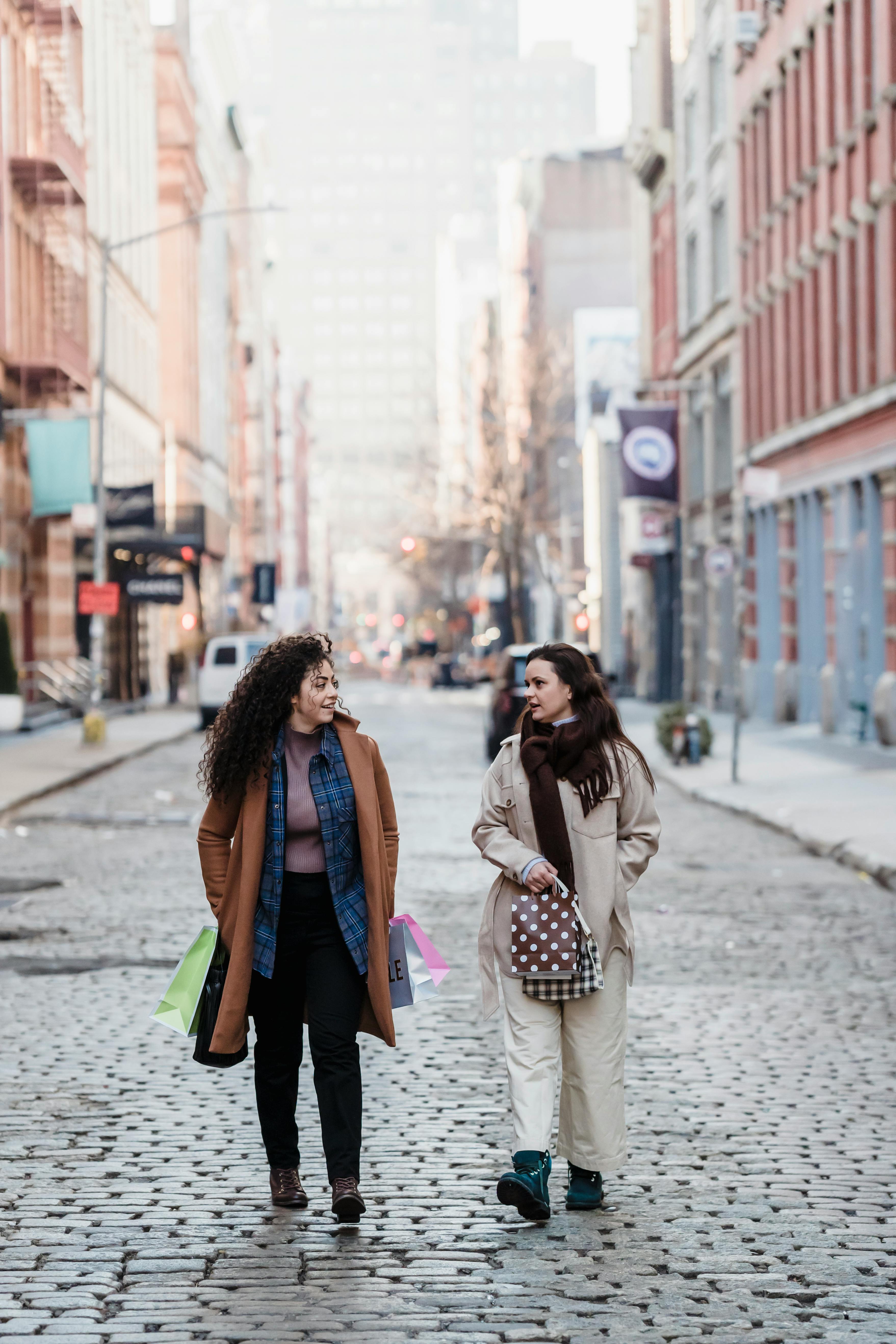 female friends with gift bags walking on paved street