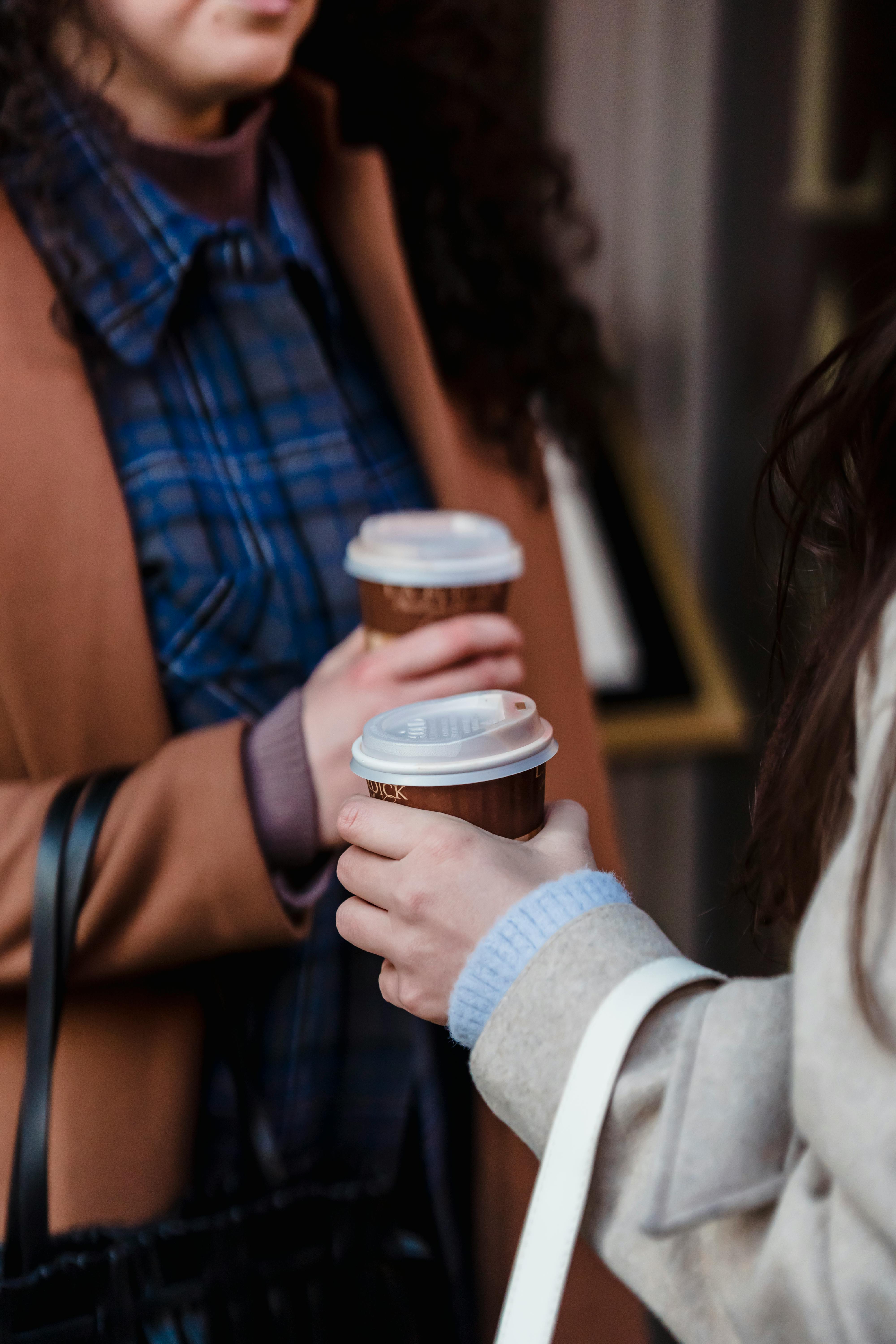 crop women with takeaway coffee on street