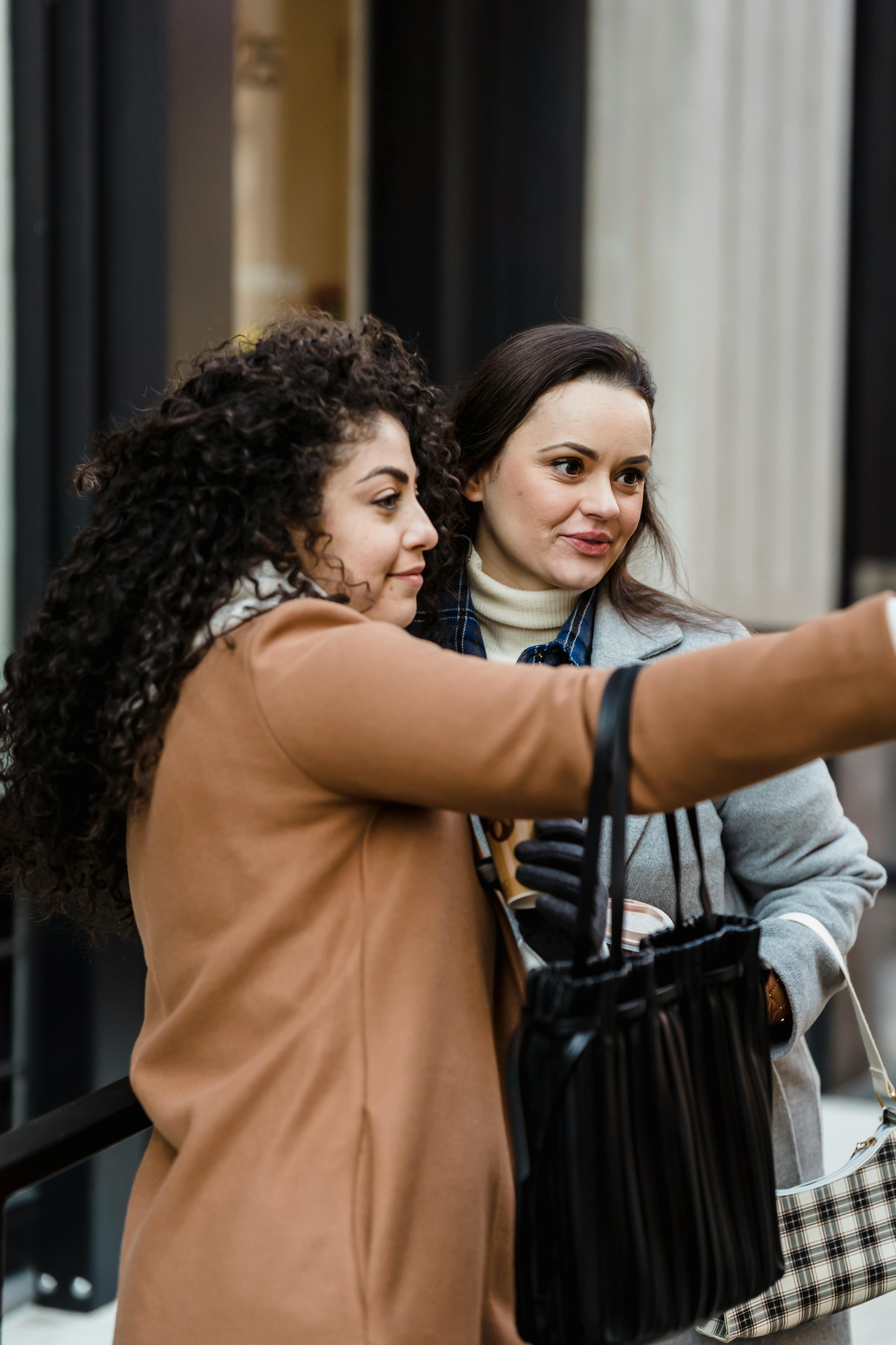 cheerful diverse women taking selfie near building