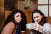Smiling multiracial women taking selfie near building