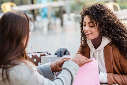 Women checking gift packages at table in street