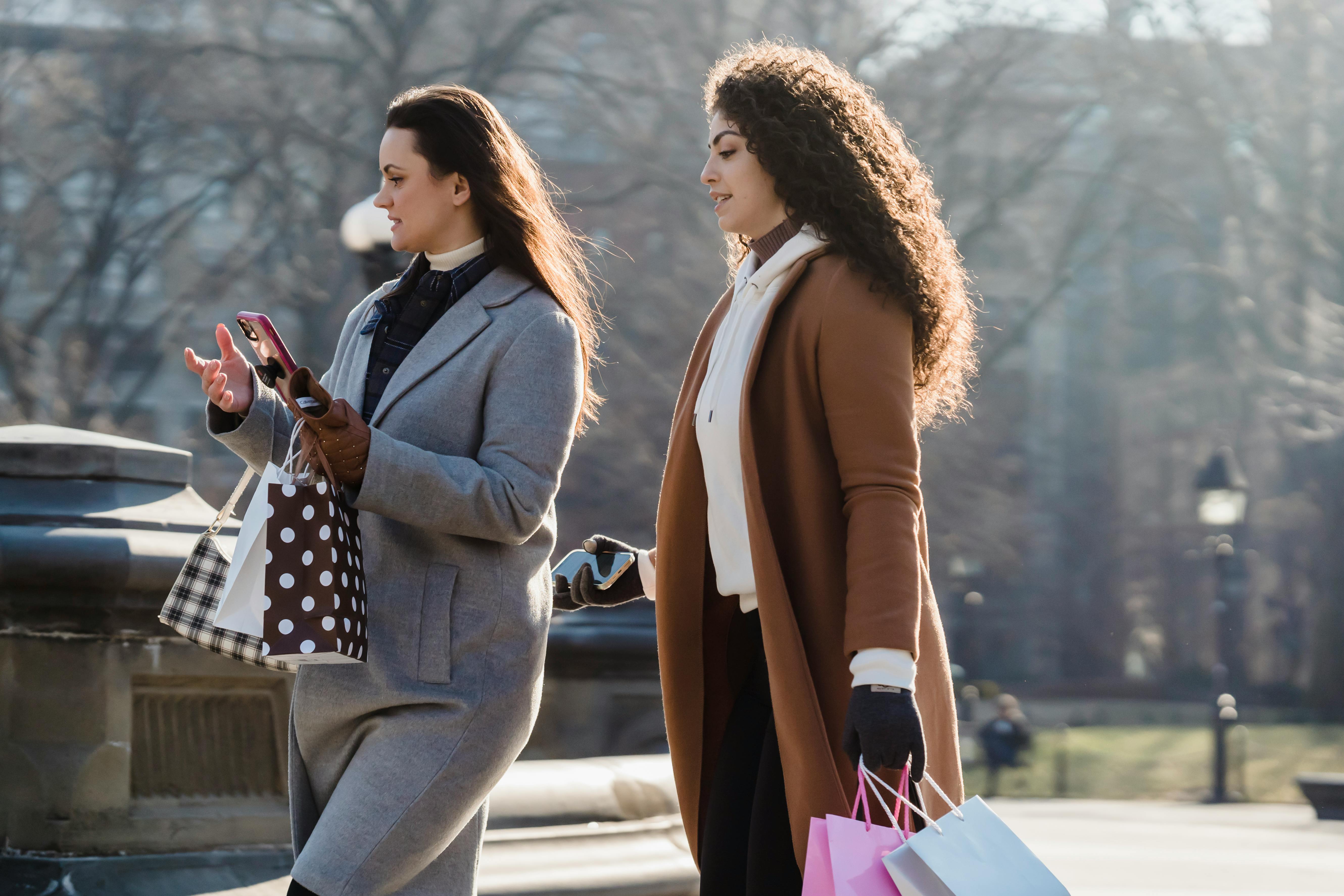 young women in outerwear walking on city street