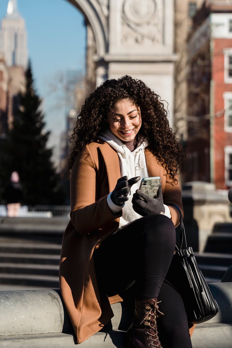 Cheerful Woman Browsing Smartphone On Spring Street