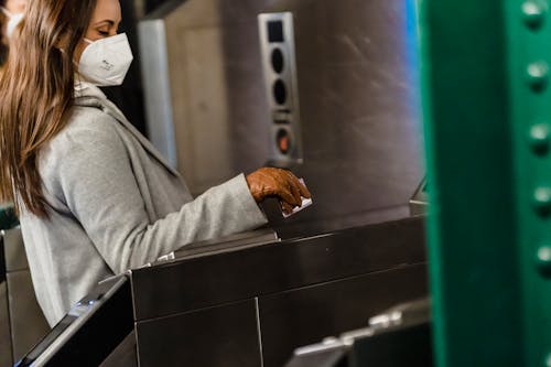 Crop woman in mask passing through turnstile in metro