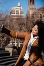 Cheerful young female in warm clothes taking selfie on smartphone while sitting on street stairs on spring day