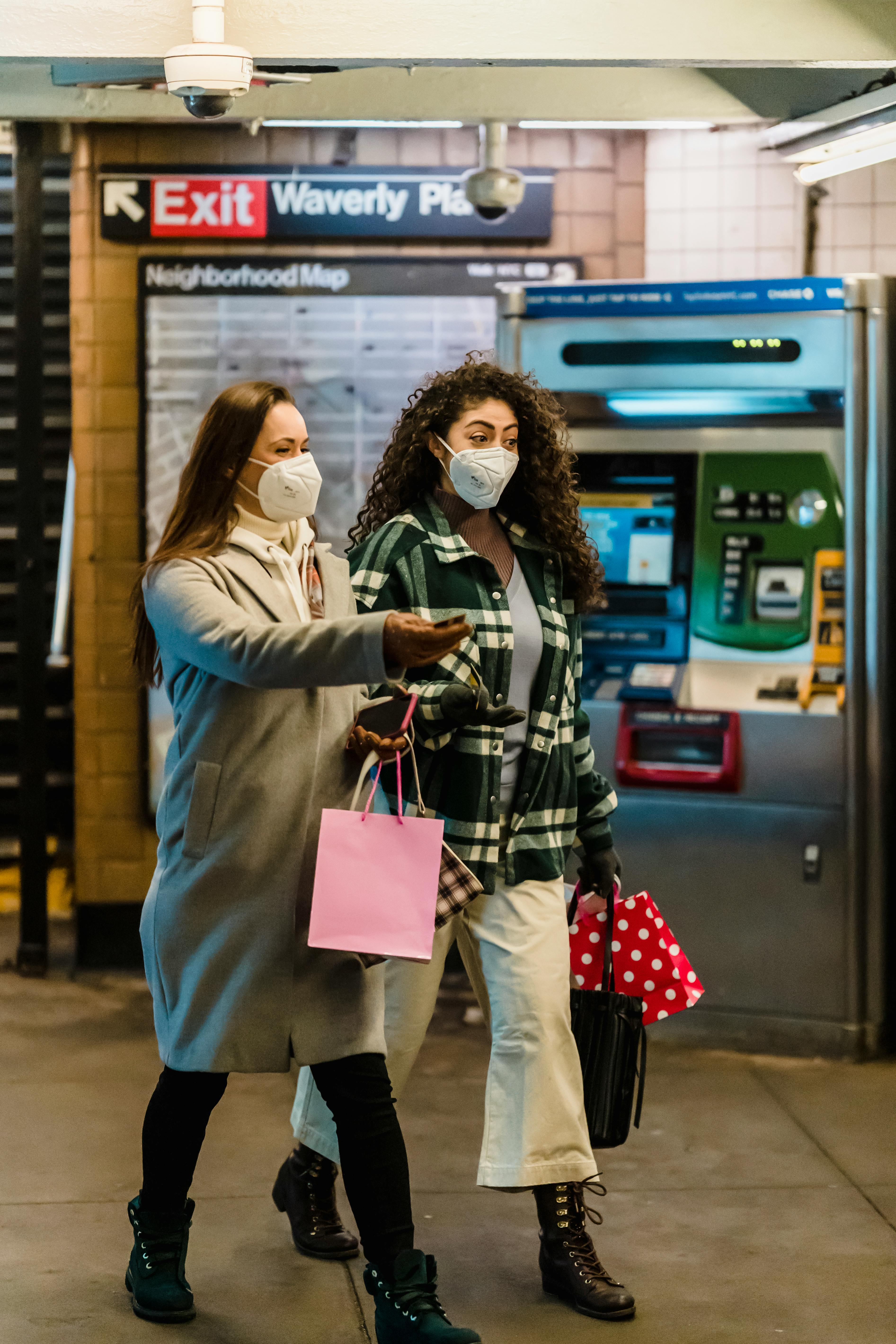 women in masks walking in subway station