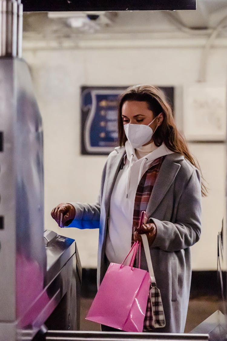 Pensive Female In Mask Passing Turnstile In Subway