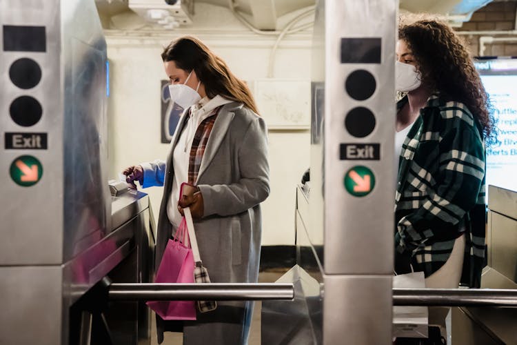 Girlfriends In Masks Near Turnstile In Underground Station