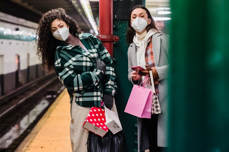 Ladies In Masks In Subway With Phone And Shopping Bags