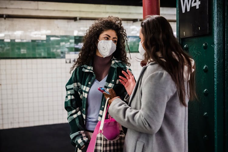 Ladies In Masks With Phone On Subway Station