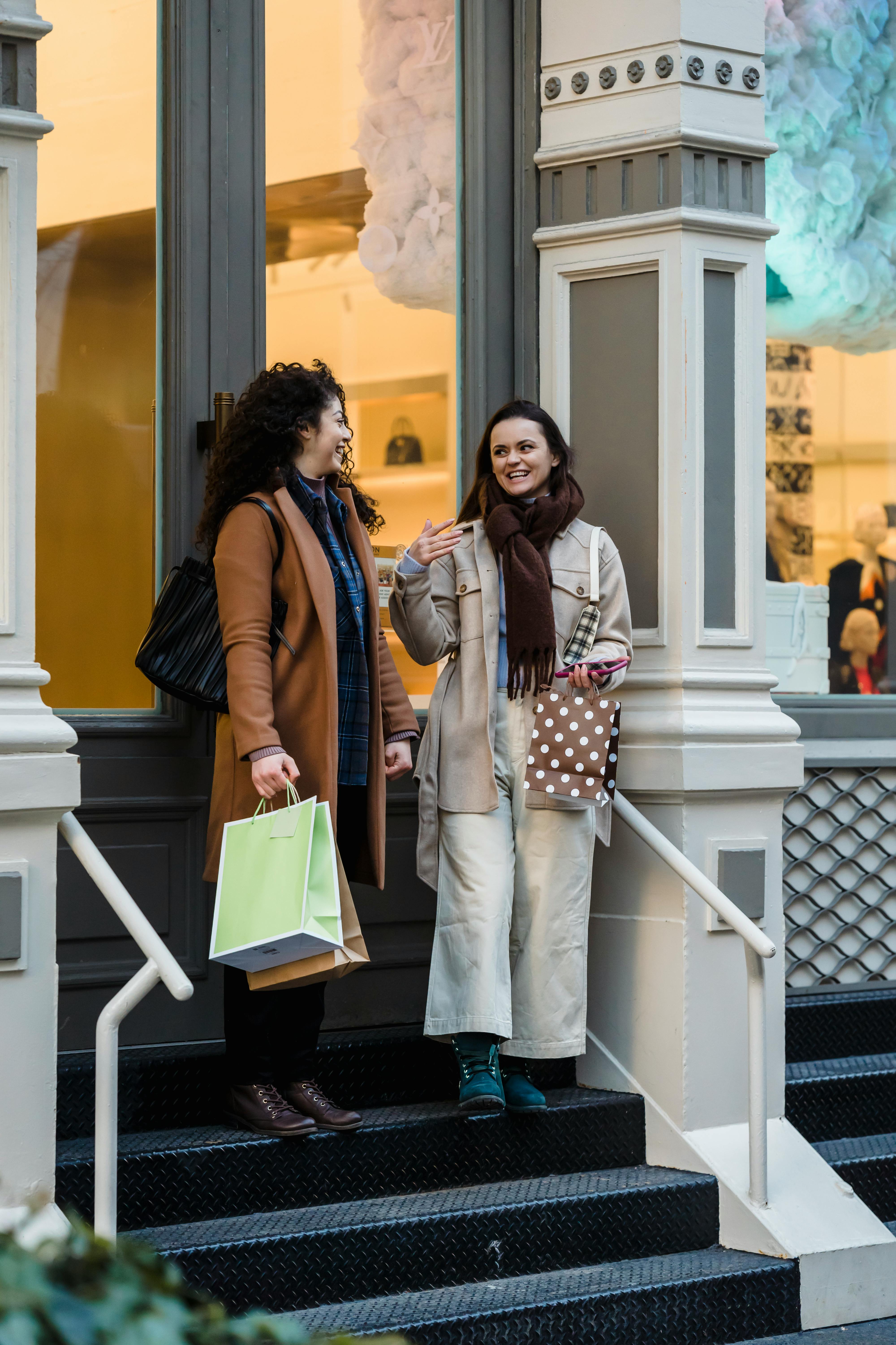 smiling young women chatting on boutique porch