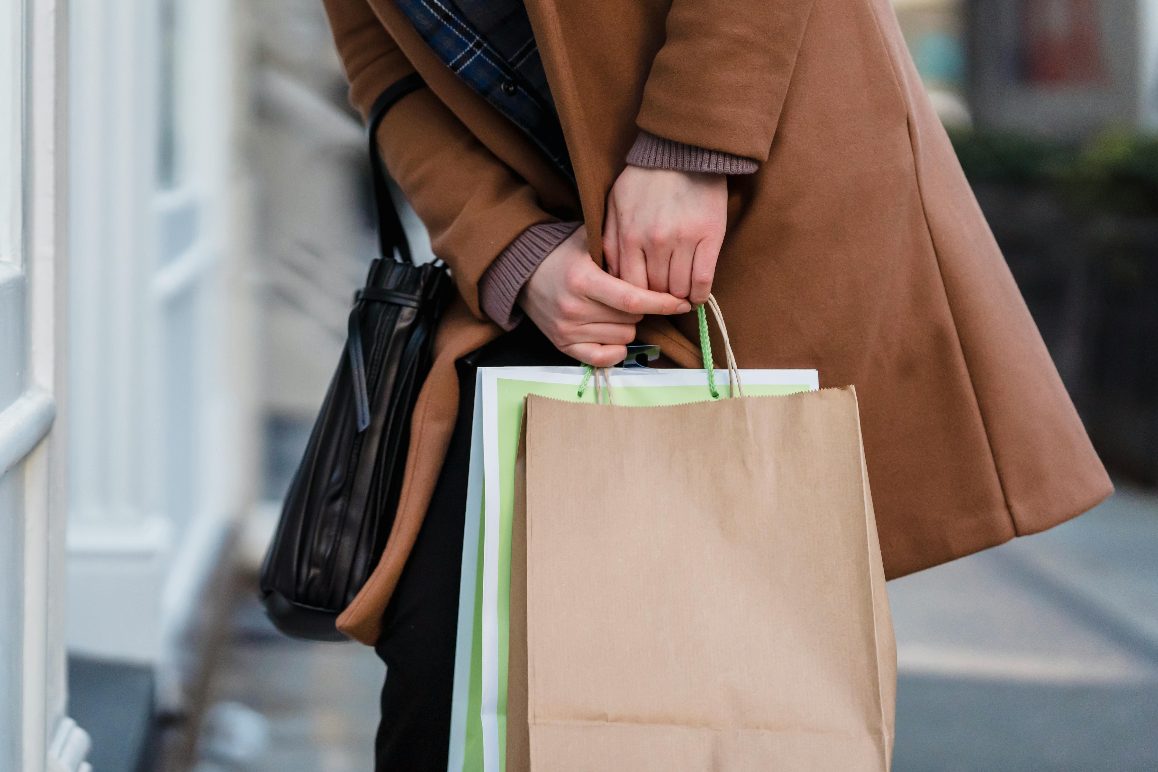 woman in coat standing with paper bags in hands