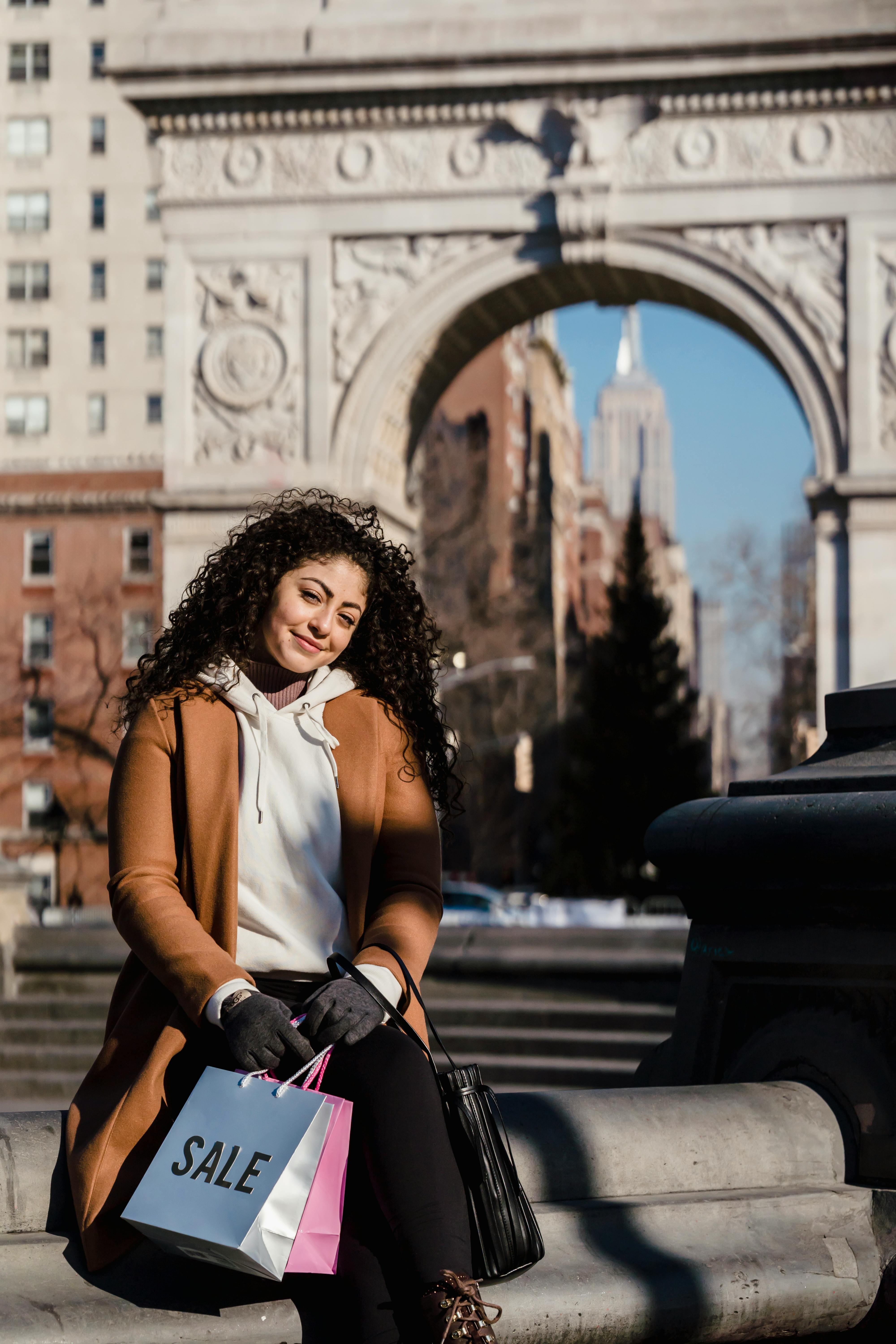 smiling woman with shopping bags sitting on border