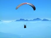Person Doing Paragliding Above Clouds during Daytime