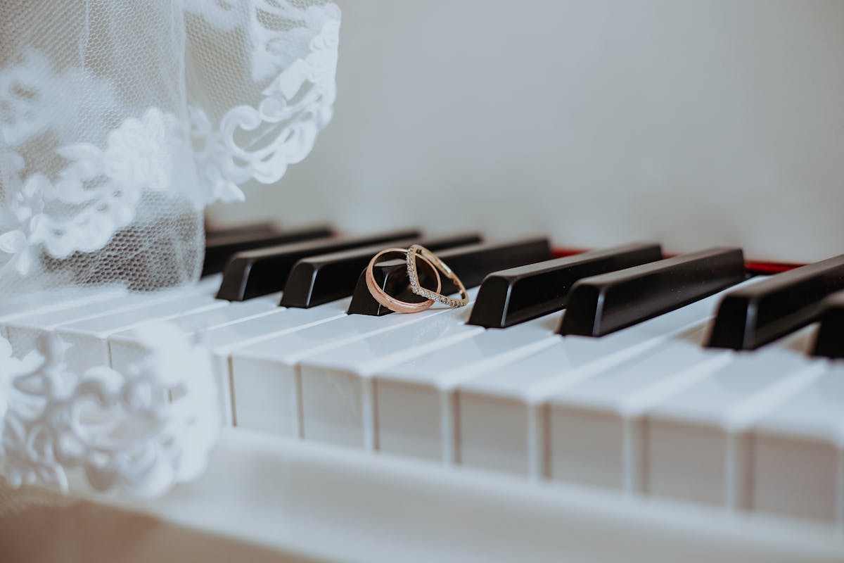 Golden rings on piano keyboard under veil with ornament during festive event in daytime