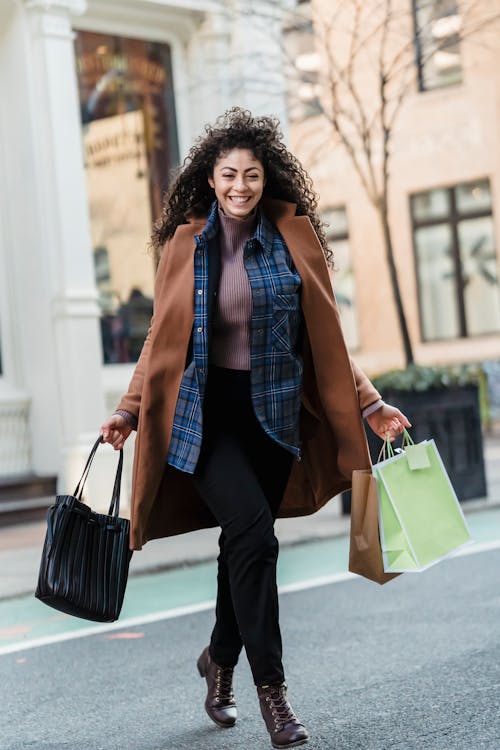 Cheerful woman with shopping bags running on street