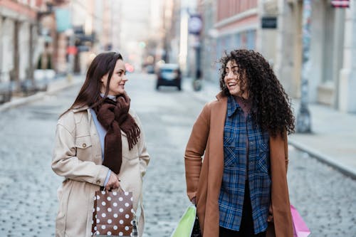 Happy multiethnic girlfriends walking with shopping bags