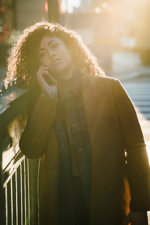 Stylish ethnic woman speaking on smartphone on street