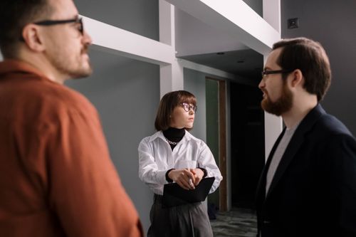 Free Three colleagues engaged in conversation in a contemporary office setting. Stock Photo