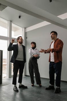 Three business professionals engaged in a lively team discussion inside a modern office space.