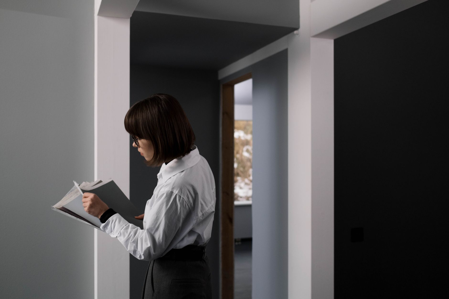 A woman in a white shirt reviews documents inside a modern office space.